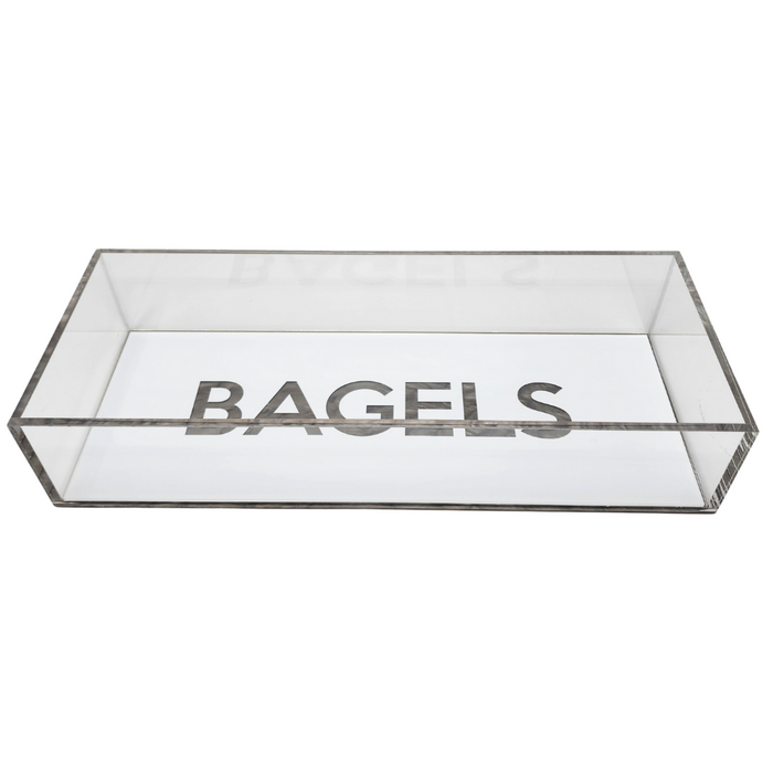 The Eye Candy Bagel Tray is a rectangular, clear silver marble acrylic box with "BAGELS" in bold capitals on the inside bottom. Food safe and lidless, it offers a modern touch for serving bagels.