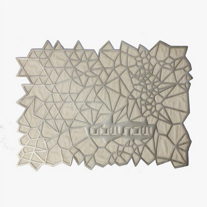The Apeloig Geometric Challah Cover is a rectangular, laser-cut piece with an abstract pattern of white and light gray polygons and triangles, shown on a plain white background.
