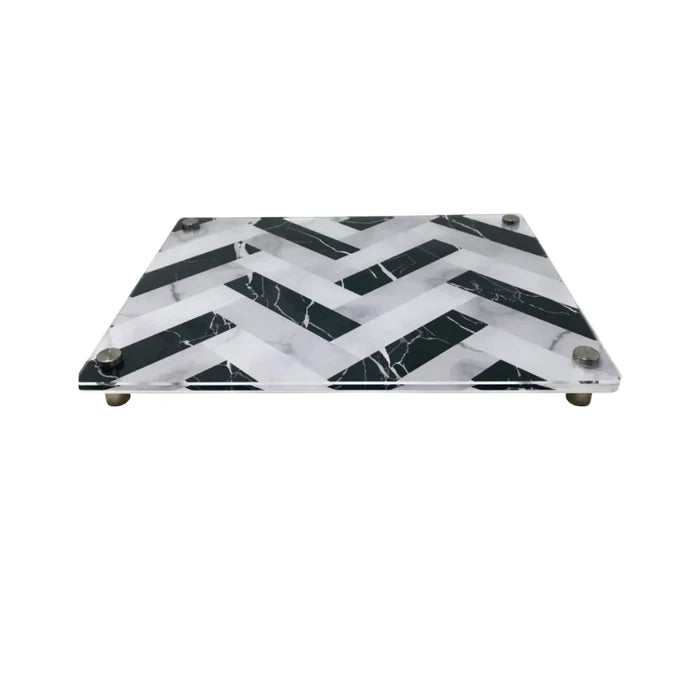 The Eye Candy Raised Serving Board Marble features a black and white chevron pattern and sturdy metal feet—a stylish choice for serving sushi or as a modern challah board.