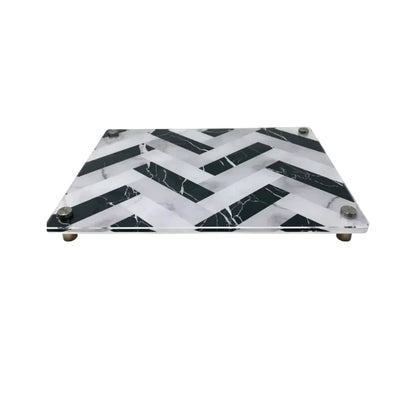The Eye Candy Raised Serving Board Marble features a black and white chevron pattern and sturdy metal feet—a stylish choice for serving sushi or as a modern challah board.